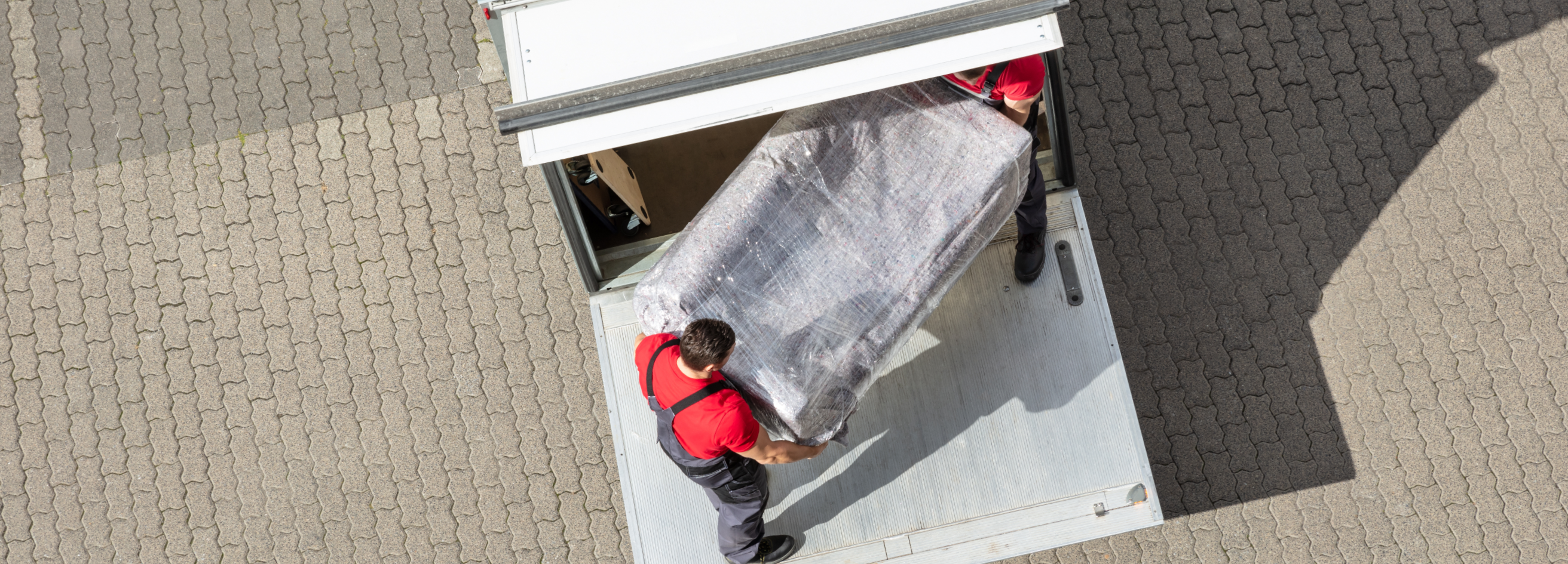 An Elevated View Of Male Mover Unloading The Furniture From Truck On Cobblestone Pavement_